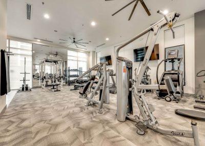 Luxury fitness center with commercial style machines, free weights, and two flatscreen televisions.